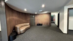A hallway with a curved leather sofa, a door with a number, and a fire extinguisher. - Alpine Heights 11B - Mt Hotham (Hotham Heights)
