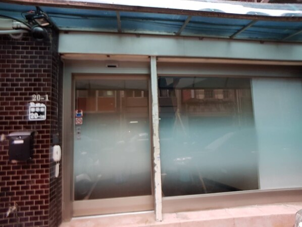 A building entrance with a glass door, a brick wall, and a metal roof. - Sumiyosh 20-1 (Taipei)