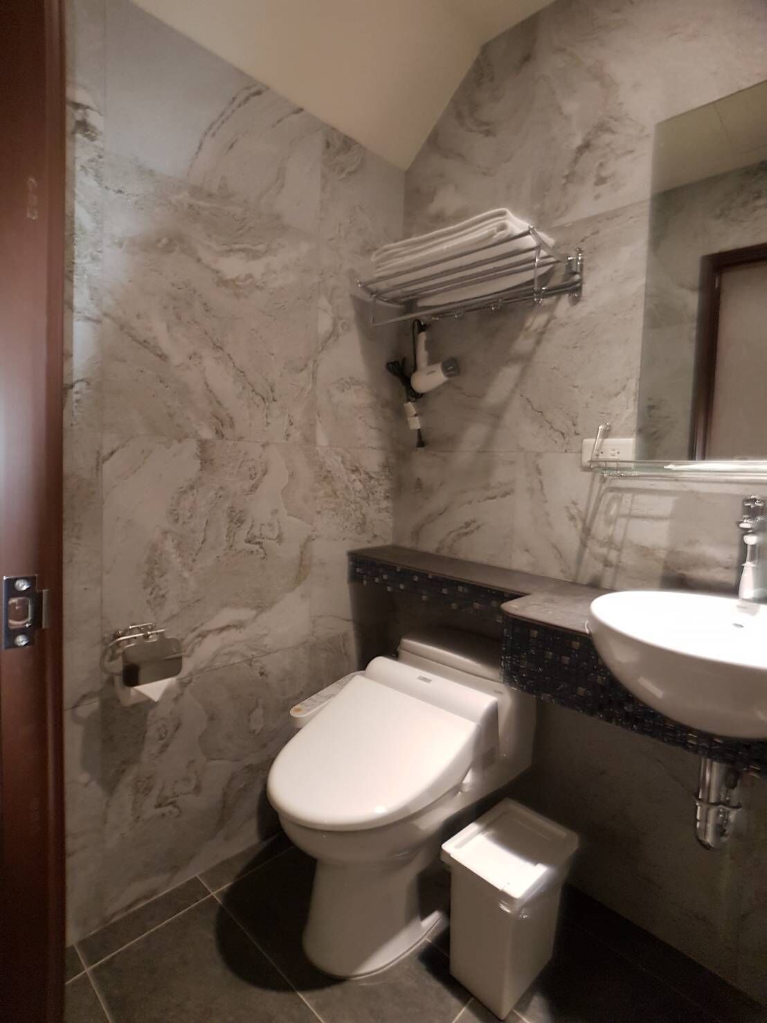 A bathroom with a toilet, sink, and towel rack.