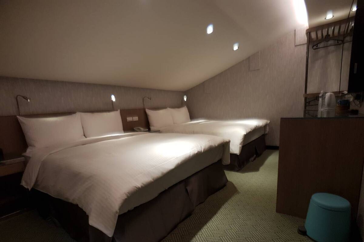 Habitació d'hotel amb dos llits, un escriptori i un petit tamboret.