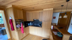 Une cuisine compacte avec des meubles en bois, un four en acier inoxydable et un plan de travail noir.