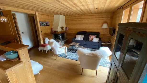 L’intérieur d’un chalet confortable, avec une cheminée, un canapé et un coin repas.