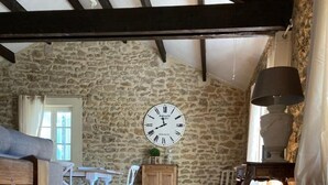 A rustic interior with a stone wall, wooden flooring, a round table with chairs, and a large wall clock. - Today's comfort in yesterday's mas in the heart of Provence (Suze la Rousse)