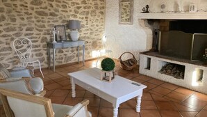 A cozy living room with a stone wall, a fireplace, and a white coffee table. - Today's comfort in yesterday's mas in the heart of Provence (Suze la Rousse)