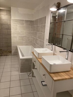 Bathroom features a large bathtub, double sinks, and ample storage.