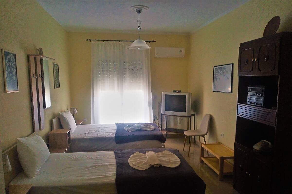 A hotel room with two beds, a television, a desk, and a cabinet.