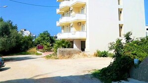A multi-story building with balconies, a clear sky, and some greenery around. - Alkioni City Apartments (Chania)
