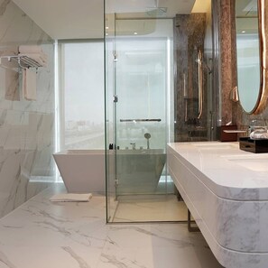 Une salle de bain moderne dotée d’une douche à parois de verre, d’une grande baignoire et d’un meuble-lavabo avec un miroir.