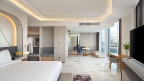 A modern hotel room with a large bed, a seating area with a view, and a flat-screen TV. - Asawin Grand Convention Hotel (Bangkok)