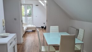 Et moderne, veloplyst rum med spisebord og stole, en sofa og et tekøkken.