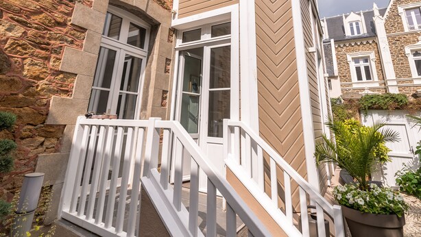 Ein Eckgebäude mit einer Stein-Fassade und einem Holzbalkon mit weißen Geländern.