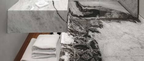 A modern bathroom with a marble vanity, a large mirror, and a glass-enclosed shower.
