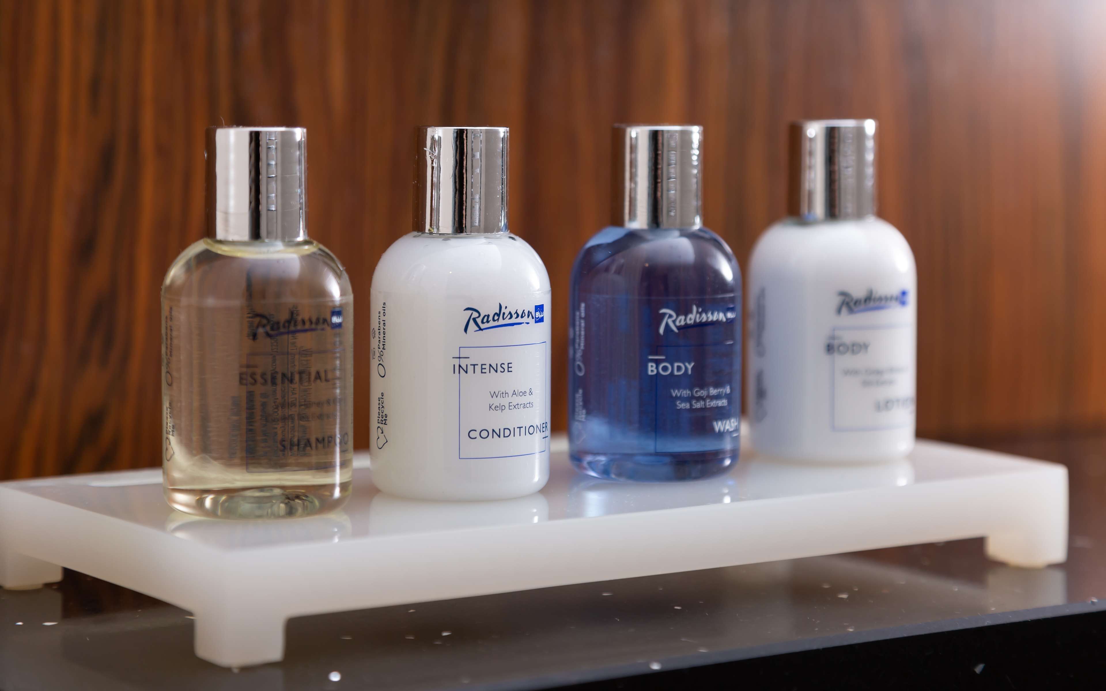 Four bottles of Radisson body wash on a white shelf.