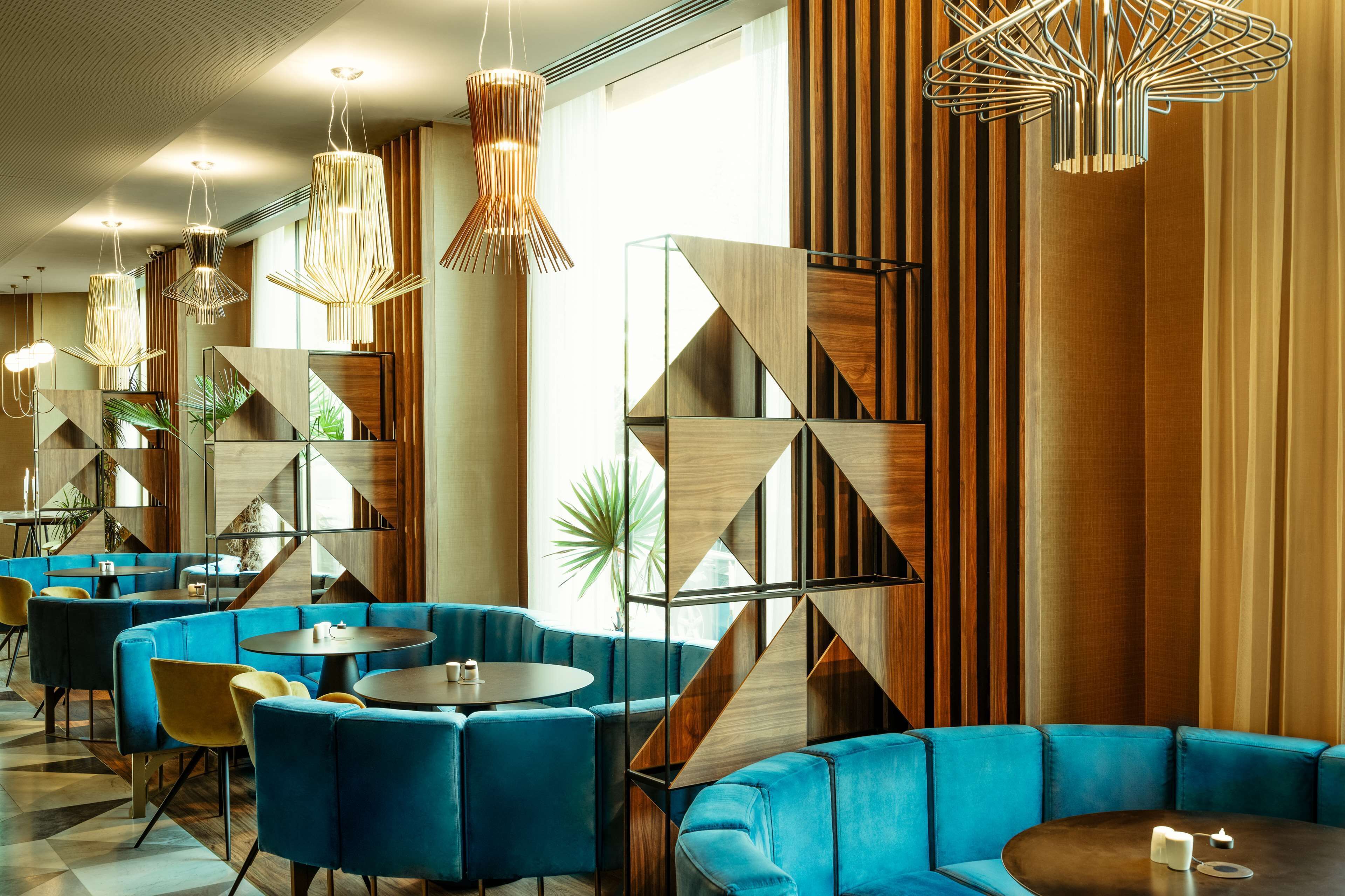 Un intérieur moderne avec des sièges bleus, des panneaux muraux aux motifs géométriques et des luminaires originaux.