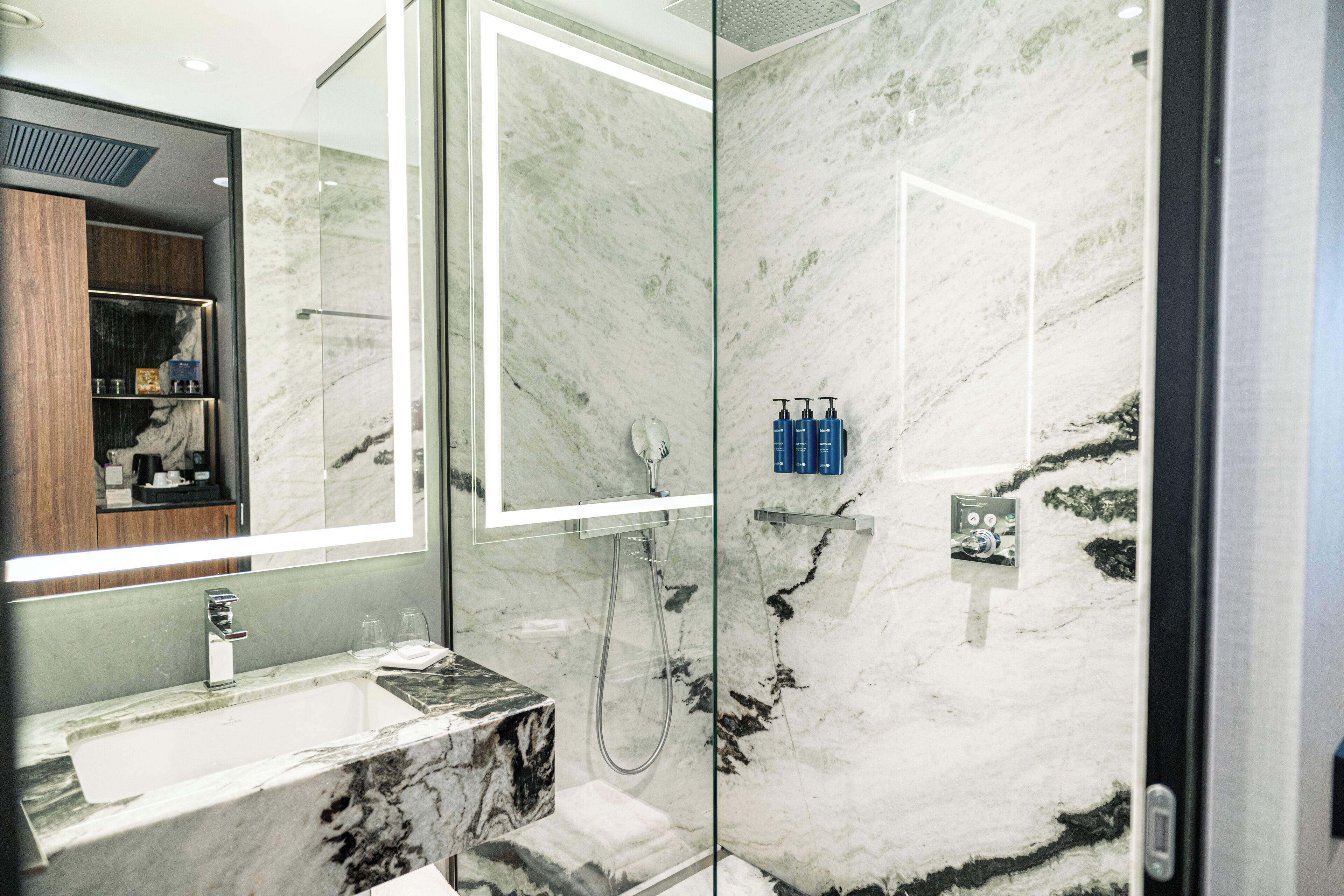 Une salle de bain moderne avec un lavabo en marbre, un grand miroir et un espace douche.