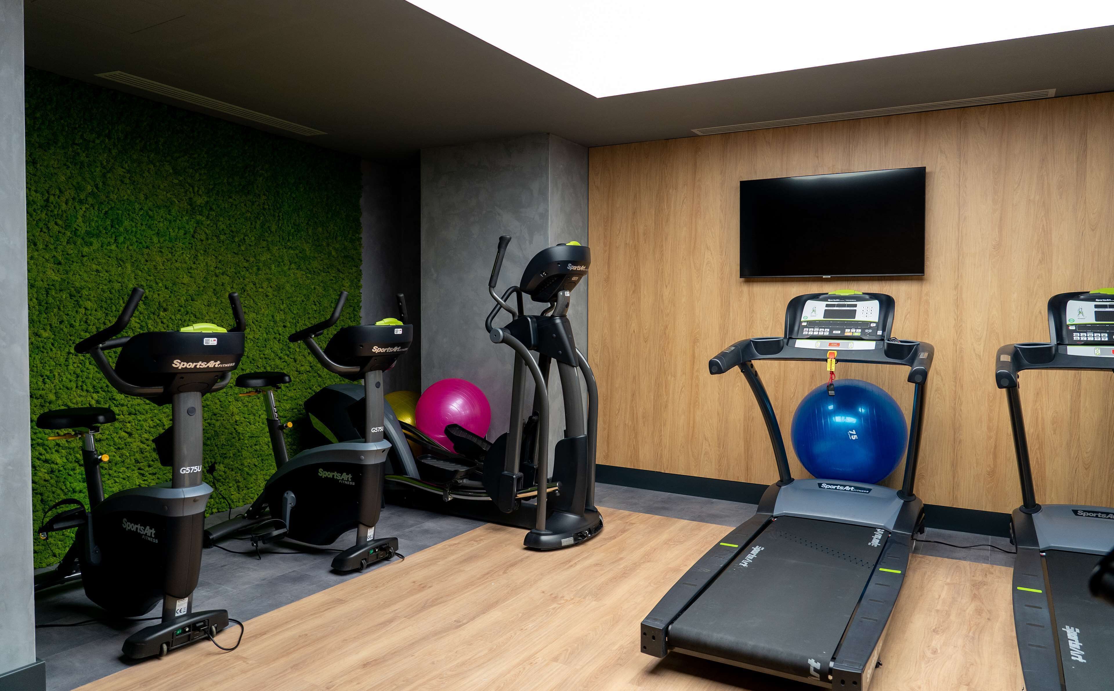 A gym with various exercise equipment including treadmills, stationary bikes, and exercise balls.