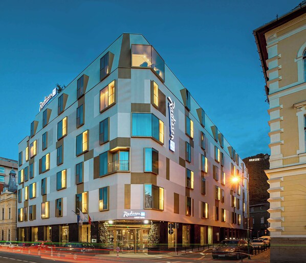 A modern hotel with a corner location, multiple balconies, and a well-lit facade. - Radisson Blu Aurum Hotel, Brasov (Brasov)