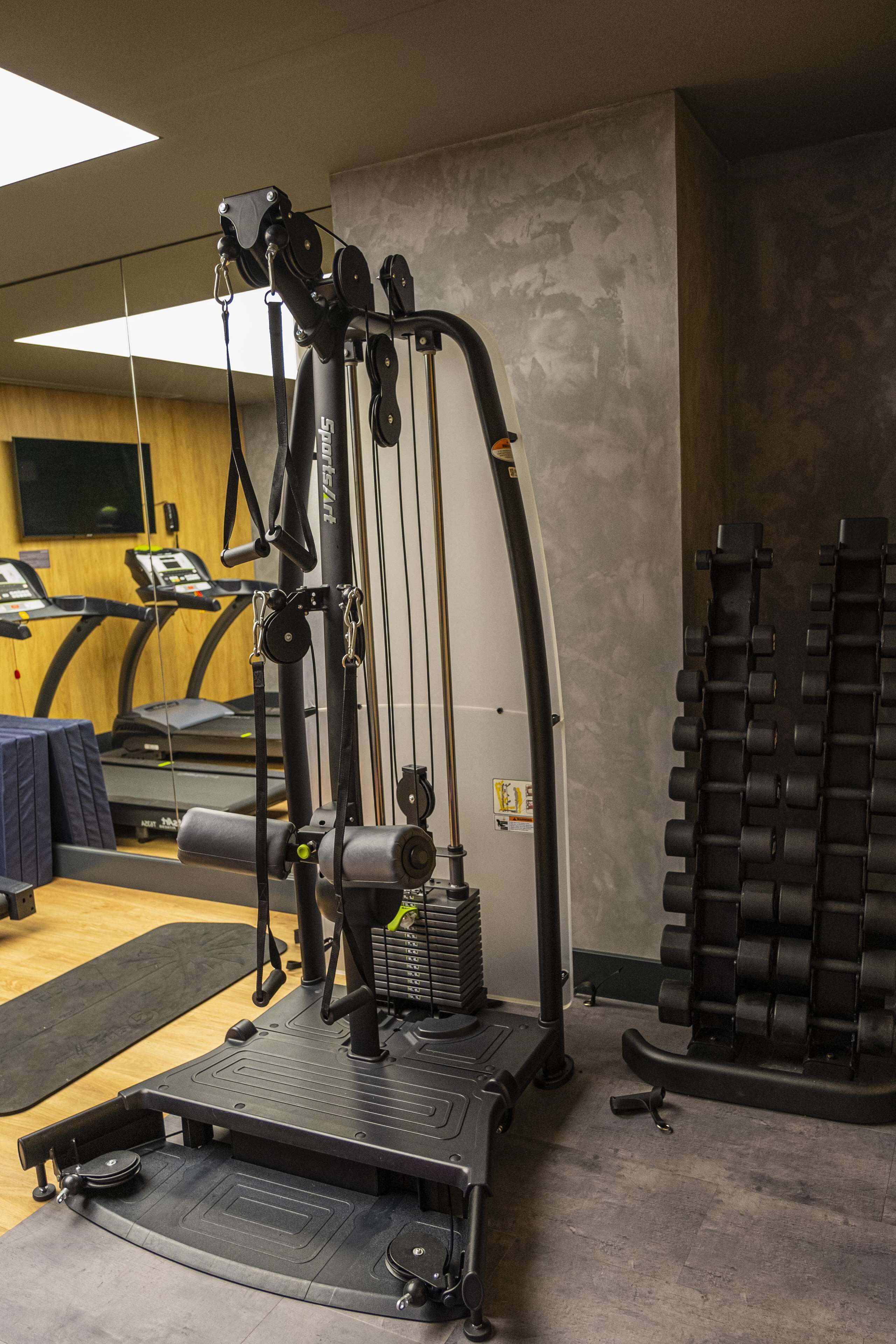 A gym with exercise equipment, a treadmill, and a weight rack.