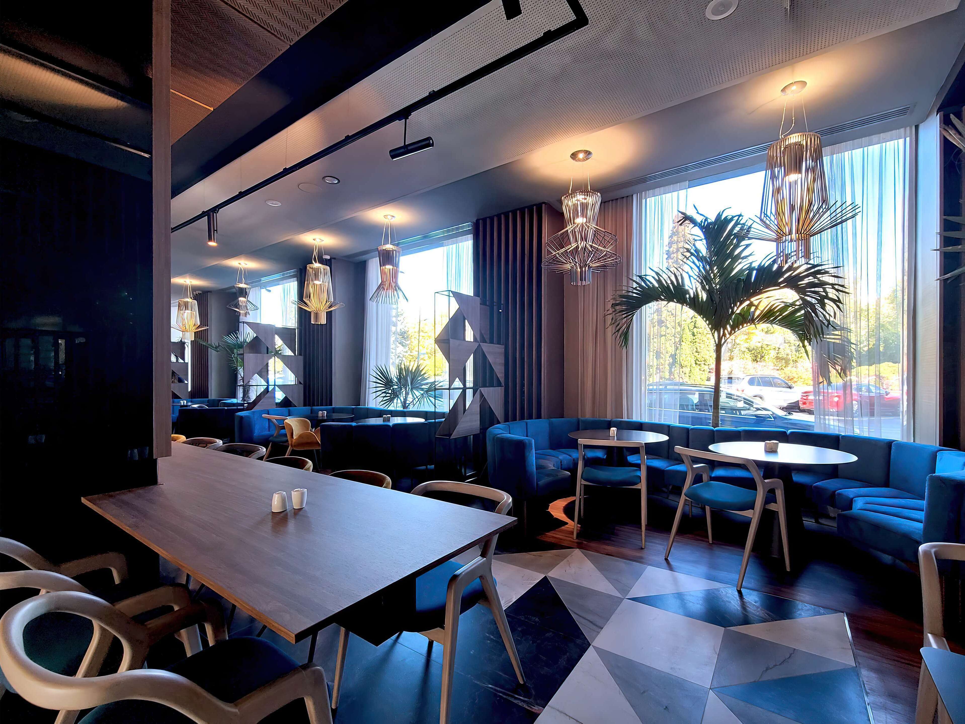 A modern interior with a wooden table, blue seating, and pendant lighting.