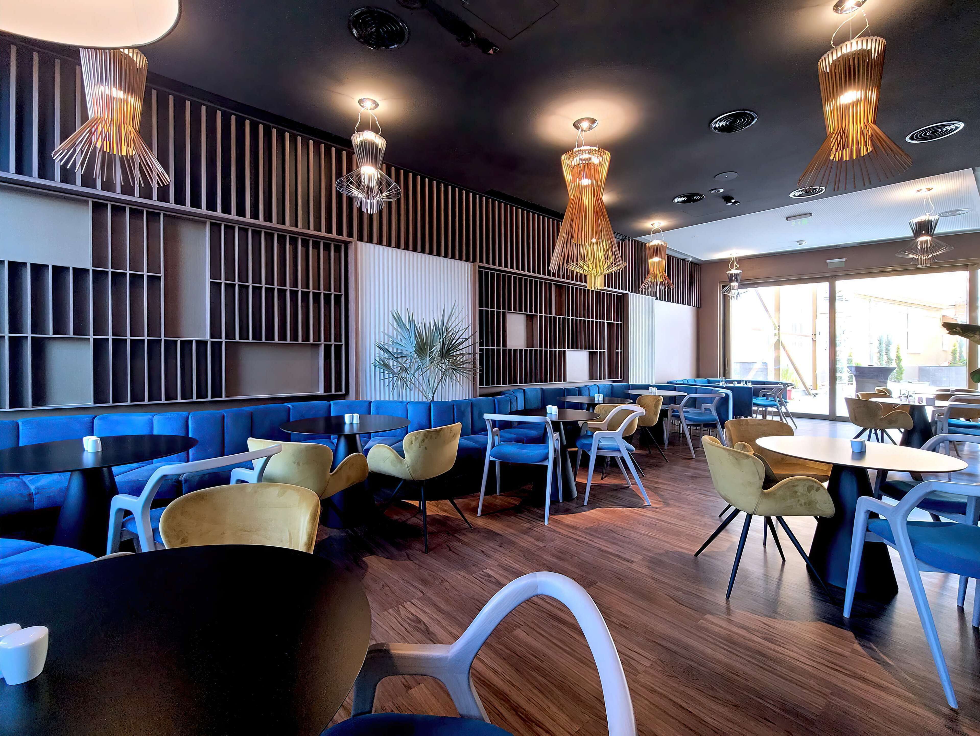 A modern restaurant interior with blue seating, wooden floors, and contemporary lighting fixtures.