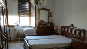 A bedroom with two beds, a dresser, a mirror, and a radiator. - Central Apartment (margherita di savoia)