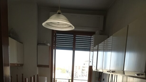A compact kitchen with a washing machine, a sink, and a dining area with chairs. - Central Apartment (margherita di savoia)