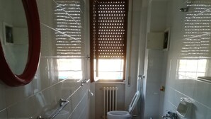 A bathroom with a bathtub, a sink, a toilet, and a window with blinds. - Central Apartment (margherita di savoia)
