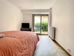 Relax in a serene bedroom with a large bed, TV, and sliding glass door leading to an outdoor space.