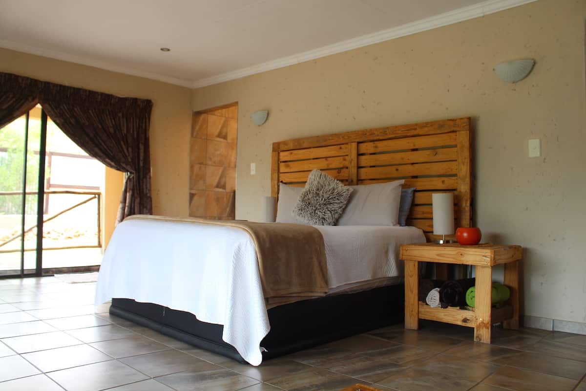 A bedroom with a bed, a nightstand, and a small wooden table.