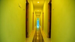 A long, narrow hallway with yellow walls and a shiny, reflective floor. - GP Residency (Gingee)