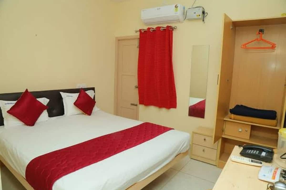 A hotel room with a bed, a wardrobe, a bedside table, and a mirror.