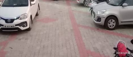 A parking area with several cars and a motorcycle.