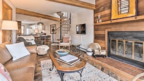 A spacious living room with a fireplace, a wooden staircase, and a cozy seating area. - Private Balcony & Resort Perks: Silverthorne Condo (Silverthorne)