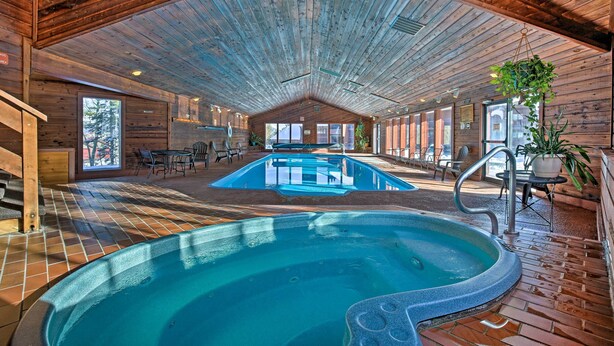 A large indoor swimming pool with a wooden ceiling and tiled floor, surrounded by seating areas and large windows. - Private Balcony & Resort Perks: Silverthorne Condo (Silverthorne)