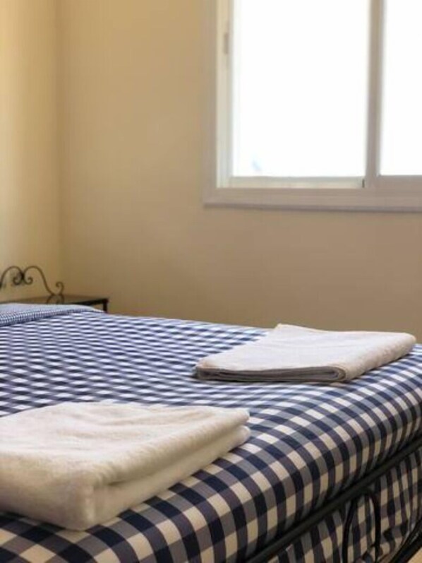 A bed with a checkered bedspread and a folded white towel. - Top Floor Private Terrace with Sea View (Oued Laou)