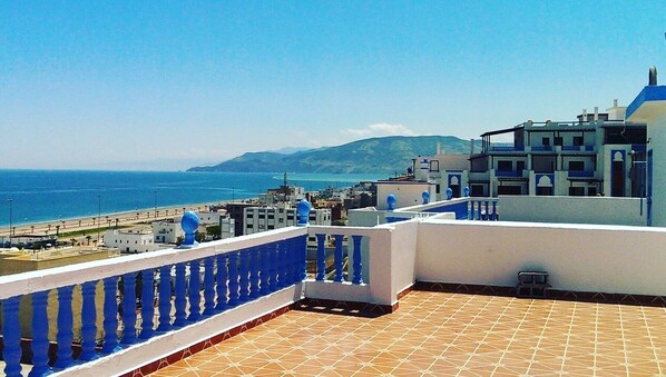 Terraço no telhado com vista para o mar e uma montanha ao longe.