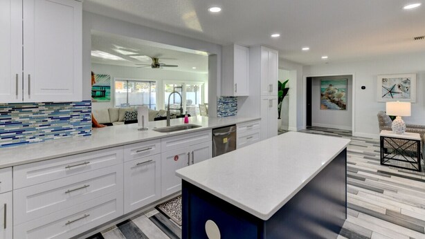 Una cocina moderna con armarios blancos, una isla grande y vistas al área de estar.