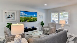 Una sala de estar moderna con un televisor de pantalla plana, dos sillones, una mesa de centro y adornos.