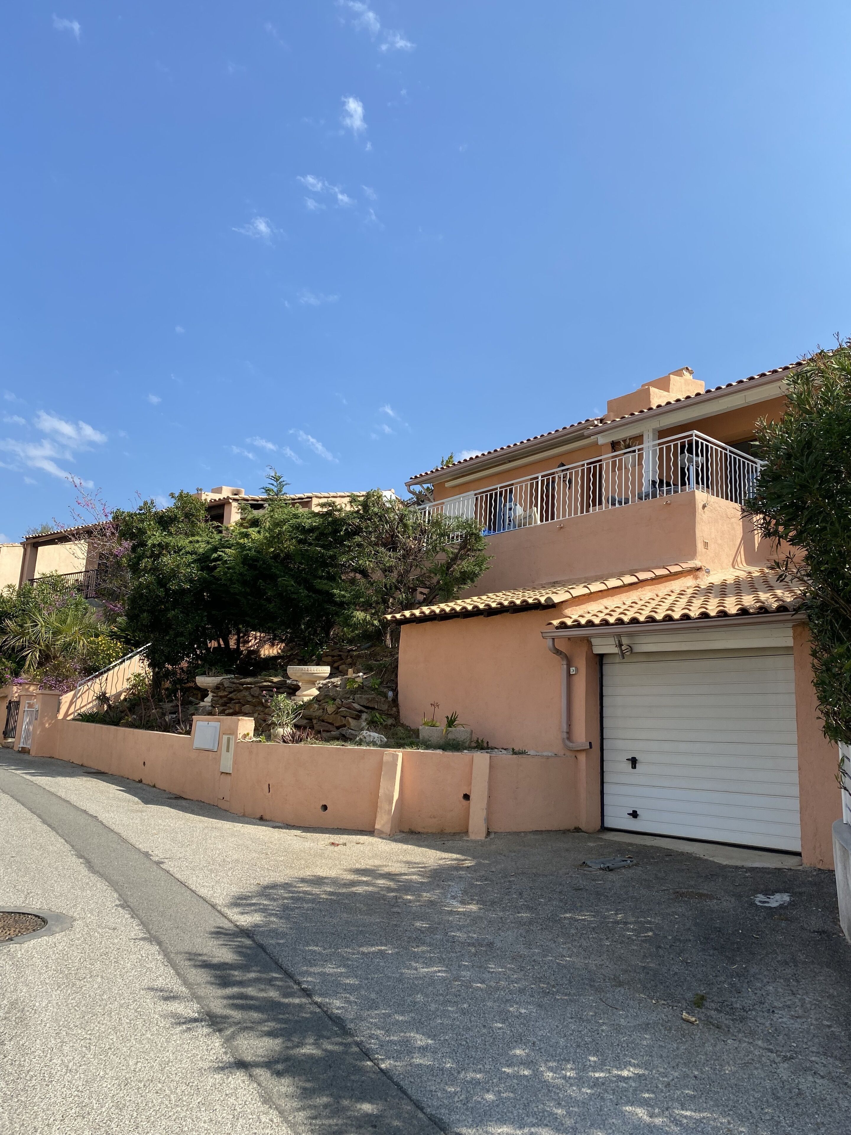 Ein Wohnhaus mit Garage, Balkon und einer Steinmauer mit Pflanzen.