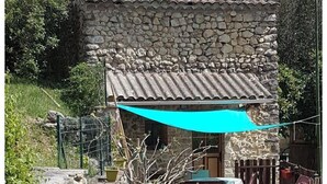 A stone building with a tiled roof, a wooden fence, and a table with chairs outside. - Village house and garden, breathtaking view (Saint-Sauveur-de-Cruzières)