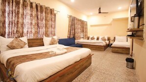 A hotel room with two beds, a wooden headboard, a TV, and a coffee machine. - Hotel Babua Hyness (Haridwar)