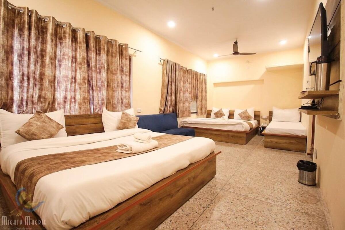 A hotel room with two beds, a wooden headboard, a TV, and a coffee machine.