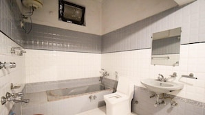 A bathroom with a bathtub, toilet, sink, and mirror. - Hotel Babua Hyness (Haridwar)