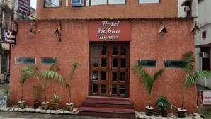A multi-story hotel with a red and beige facade, featuring a prominent entrance with a red awning and a sign that reads "Hotel Babua Wyness." - Hotel Babua Hyness (Haridwar)