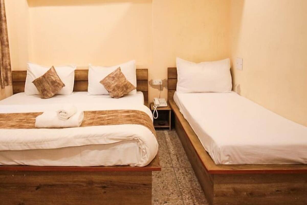 A hotel room with two beds, wooden headboards, white bedding, and a bedside telephone.
