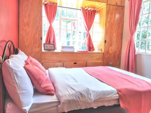Relax in a serene bedroom with a comfortable bed, bedside table, and window with curtains.