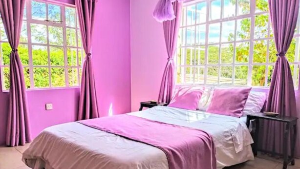 Una habitación con cama, cortinas y ventanas.