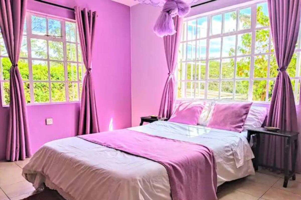 A room with a bed, curtains, and windows.