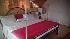 Un dormitorio con una cama, un armario y una mesita de noche.
