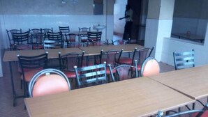 A dining area with multiple tables and chairs, a person in the background, and a kitchen area visible through an open doorway. - Pivot Hotel (Mwingi)